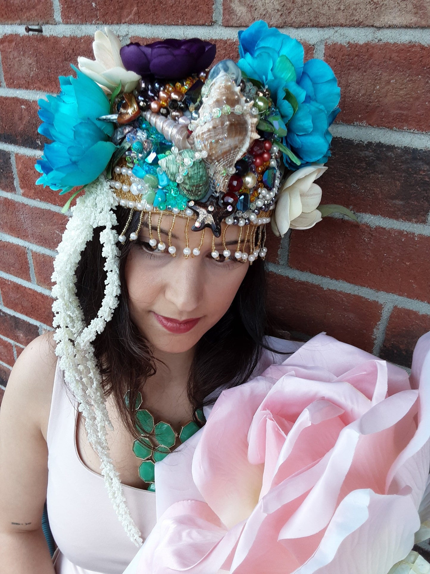 A richly detailed crown featuring hand-sewn seed beads, crystals, seashells, pearls, and layered fabric flowers.