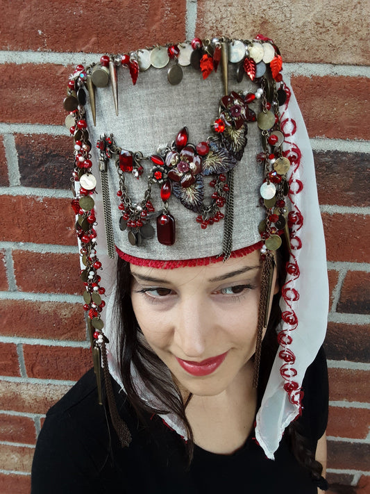 A vintage-inspired, hand-sewn crown with ornaments, coins, beads, and flowing veil detail.
