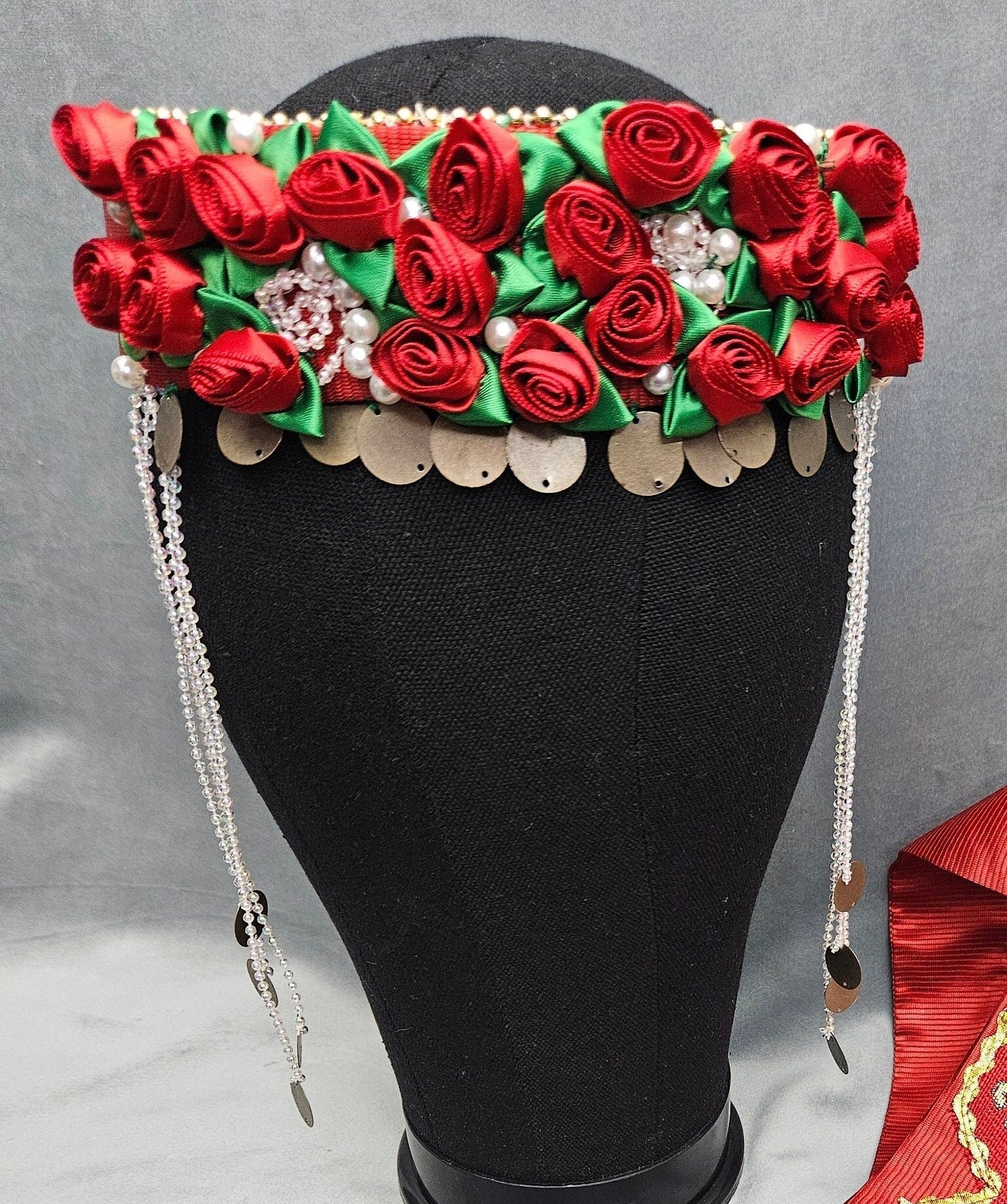 Decorative headband with red flowers and green leaves on a mannequin